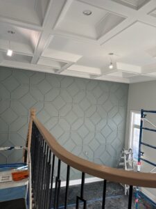 A beautifully painted accent wall with crown moulding and geometric paneling and a white coffered ceiling in a modern home interior.